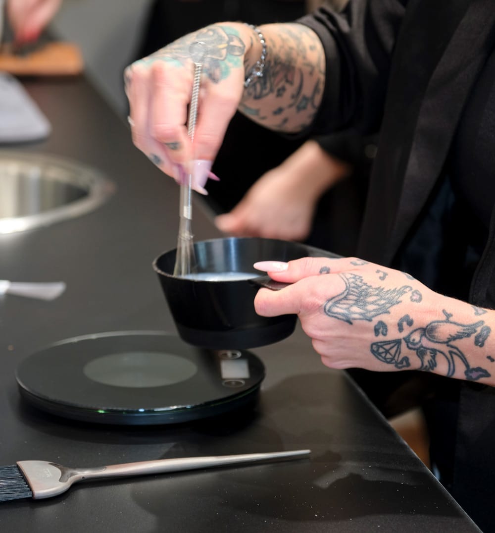 Friseursalon HEIMATFRISEURE – Friseur bei der Arbeit Friseursalon von HEIMATFRISEURE mit einem Friseur bei der Arbeit beim anmischen von Farben. Fokus auf die Hände.